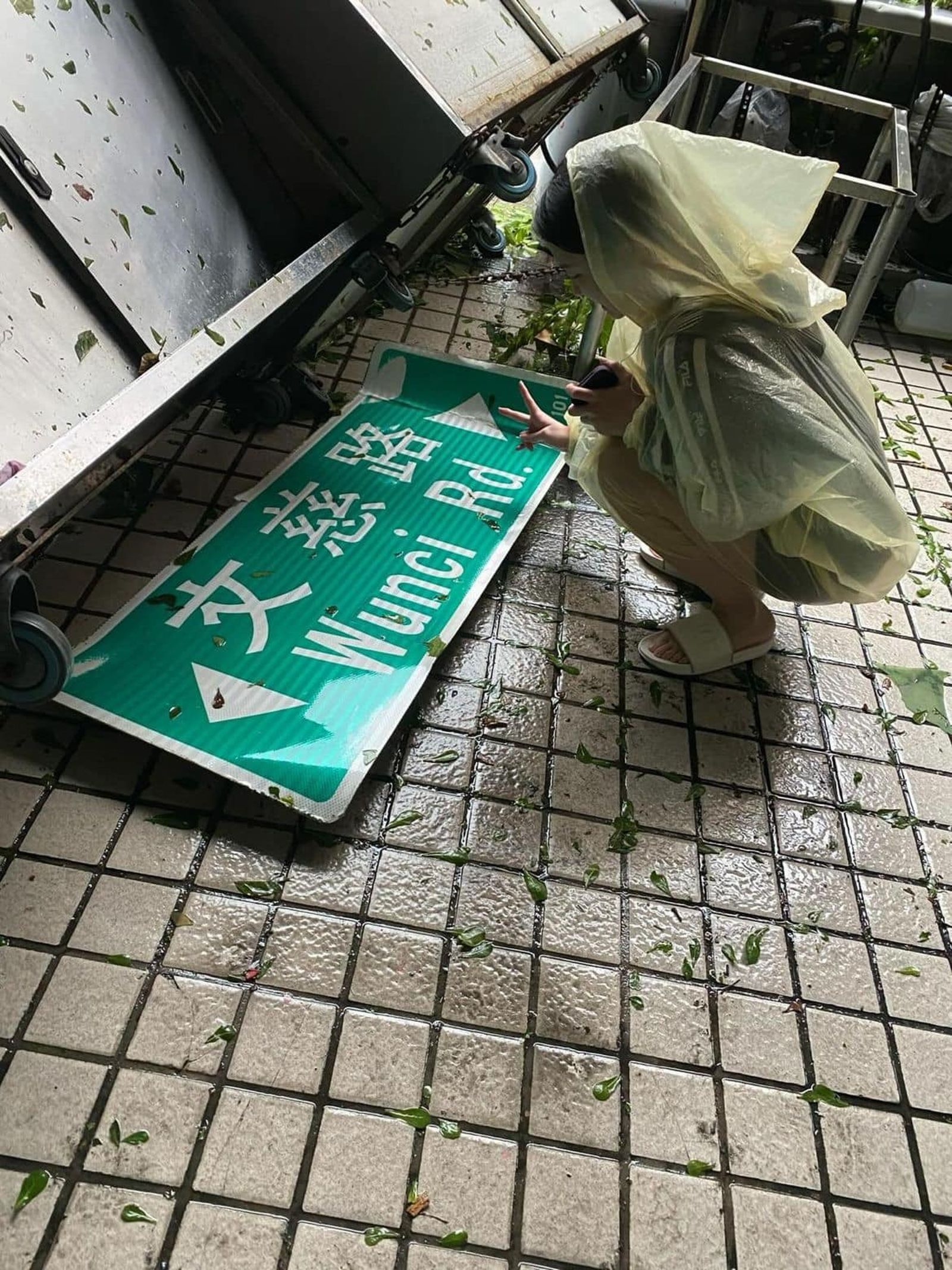 高雄人收拾家園之餘,與掉落的路牌合影。(圖/翻攝自高雄點臉書)
