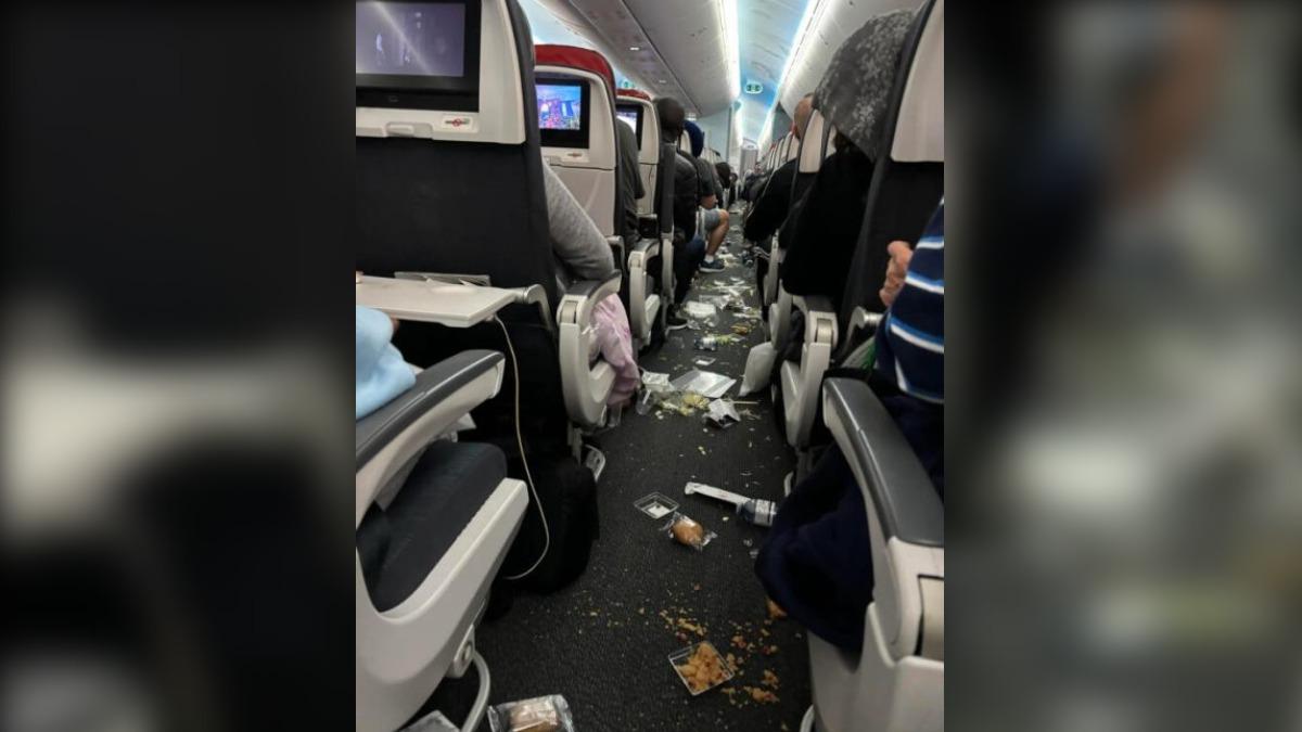 機艙走道上散落著各種物品，包括餐盒、麵包、水瓶和杯子等，現場一片狼藉。（圖／翻攝自新明日報）