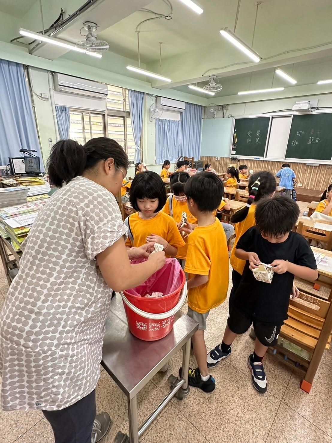 北市景美國小低年級導師教導學生如何回收牛奶紙盒。(圖/北市教育局提供)