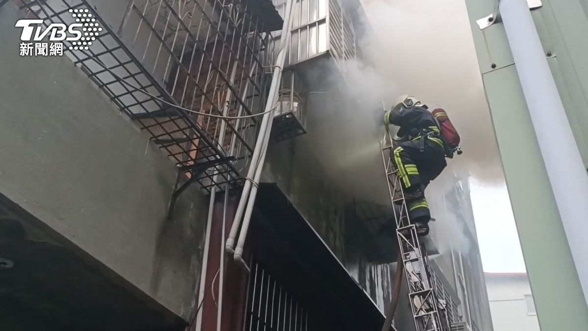 火警現場不斷地竄出濃煙,警消架梯搶救。(圖/TVBS)