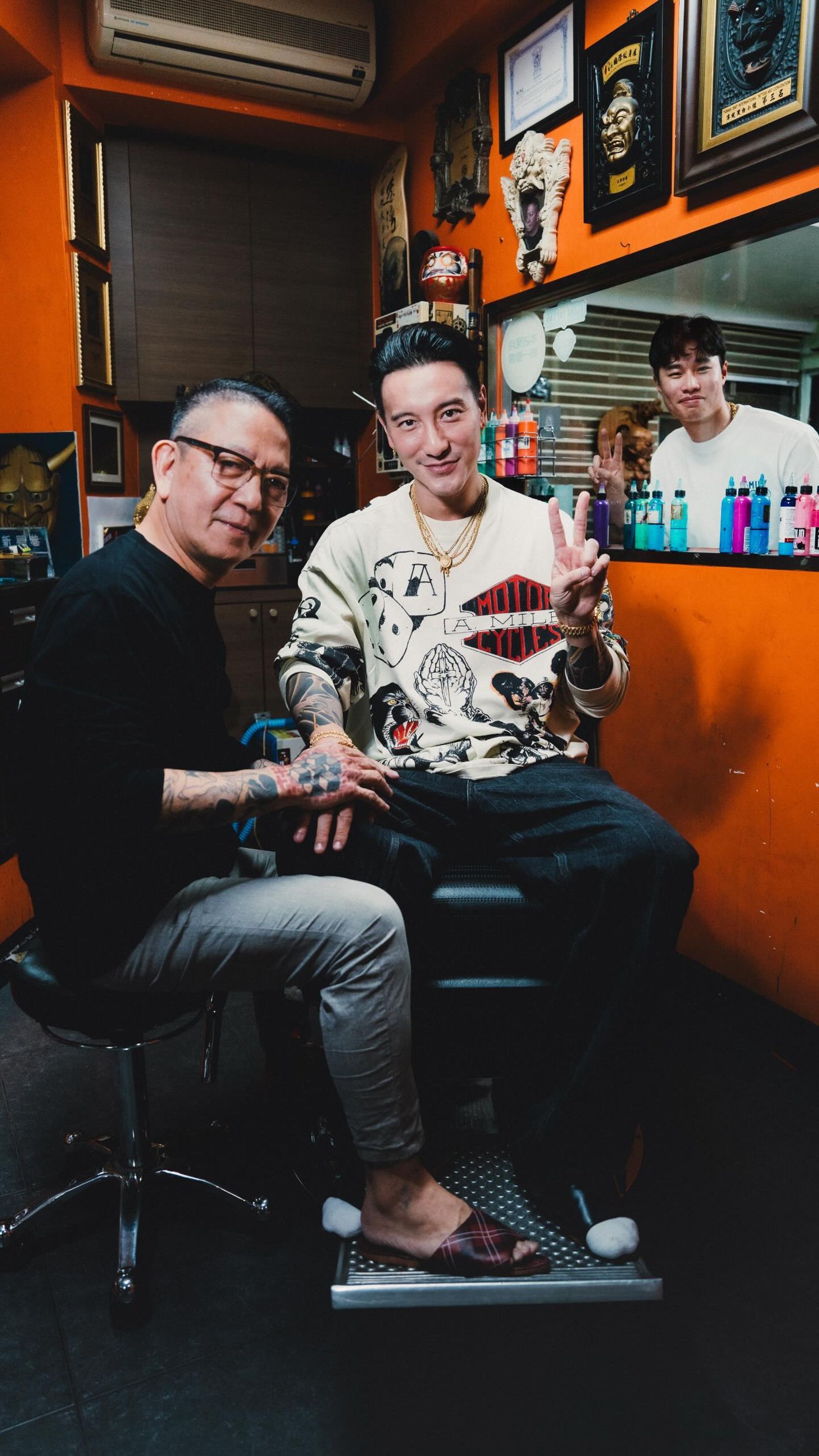 王陽明與刺青師富哥坐在小房間內,林昱珉在後方窗戶外比YA合照。(圖/翻攝自王陽明Threads)