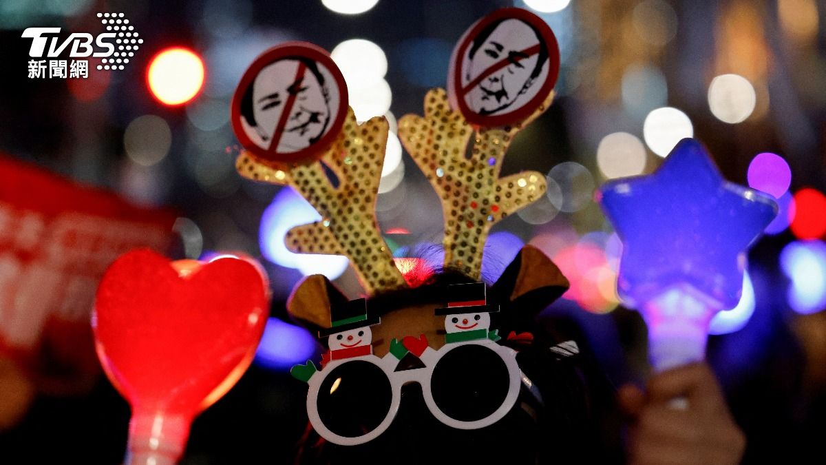 民眾戴著聖誕節頭飾,手拿螢光棒上街抗議。(圖/達志影像路透社)
