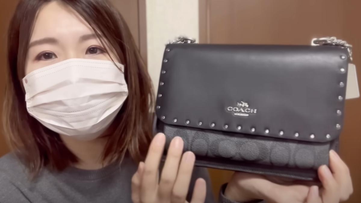日網紅先是拿出COACH福袋中的黑色肩背包。(圖/翻攝自ぶくろちゃんねる YouTube)