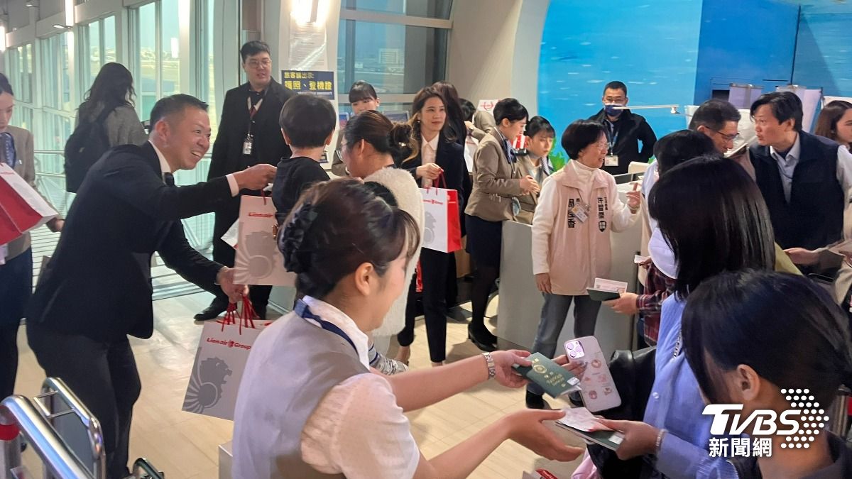 高閔琳及許智傑服務團隊在機場發上給首航旅客迎賓紀念品。(圖/林雅婷攝)