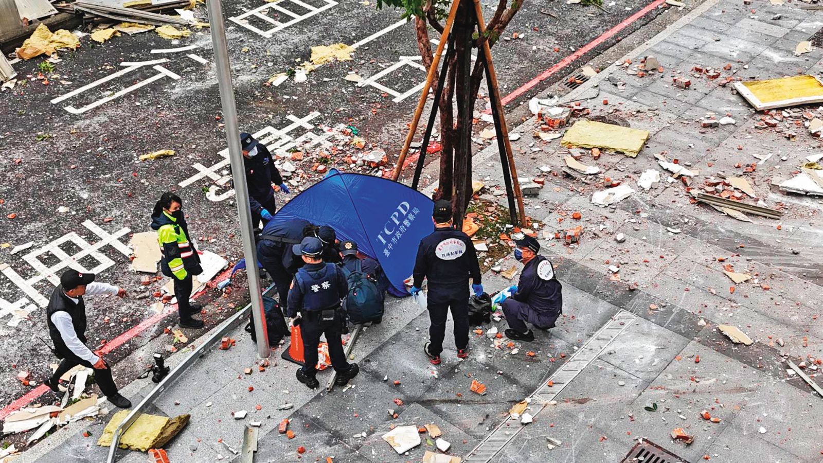氣爆當時,行經樓下的澳門籍夫妻,不幸遭重物砸死,警方用帳篷帷幕遮蔽遺體,等候法醫相驗。(圖/民眾提供)