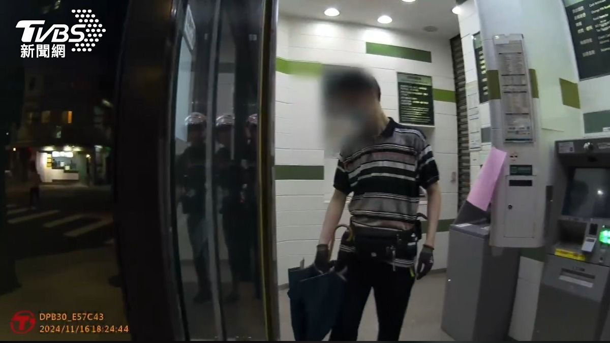 男撐開傘阻擋民眾使用ATM。(圖/TVBS)