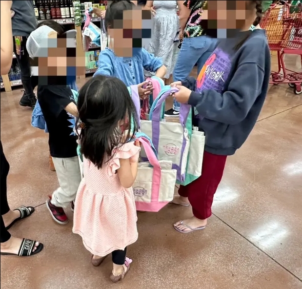 一群小朋友每個人手上都拿著和他們身材相比不迷你的手提袋。（圖／世界日報提供）