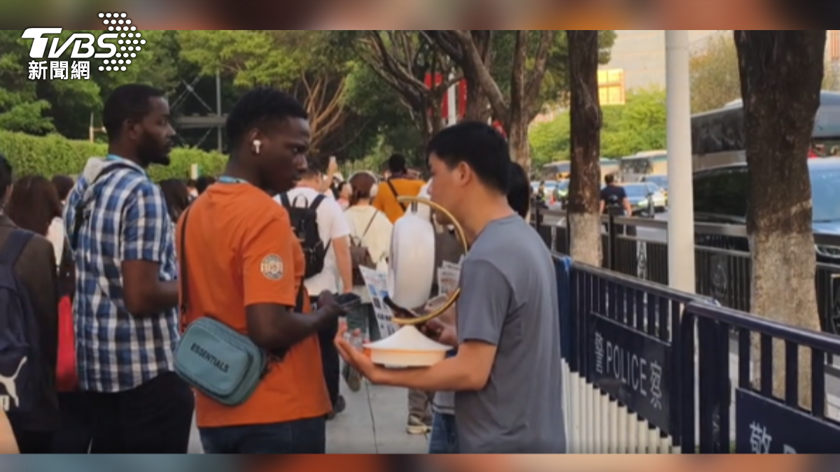 TVBS特派記者直擊,廣交會門口,許多付不起展場攤位租金的小型業者,拿著產品目錄吸引國外採購商。(圖/謝賢熺 攝)
