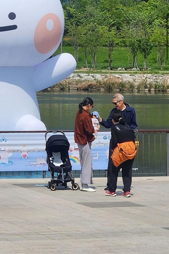 金珉禧(左)被拍到抱起嬰兒,不過被認為可能是女性路人的小孩。(圖/翻攝自韓網)