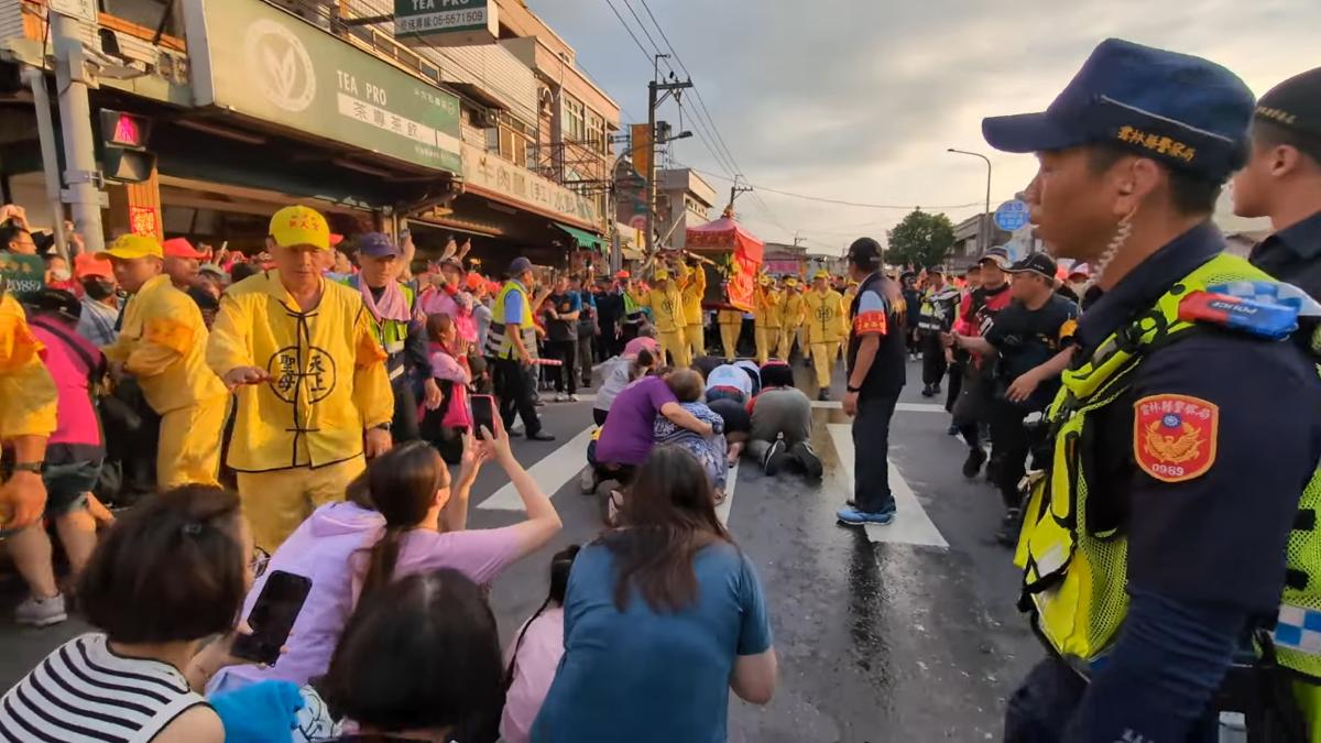 一名紫衣婦人熱心抱著阿嬤跪地。(圖/翻攝自YouTube-白沙屯媽祖網路電視台頻道)