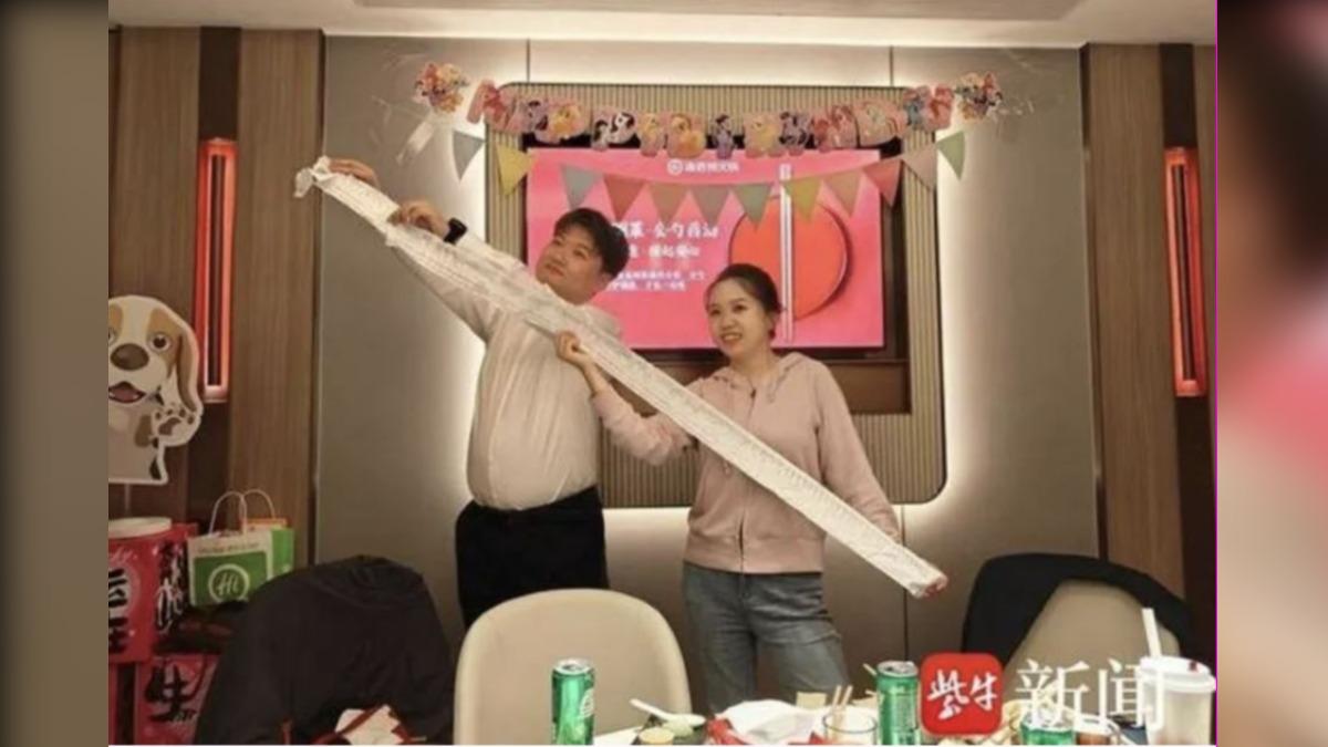 新人夫婦拉起2公尺長的婚禮帳單。(圖/紫牛新聞)