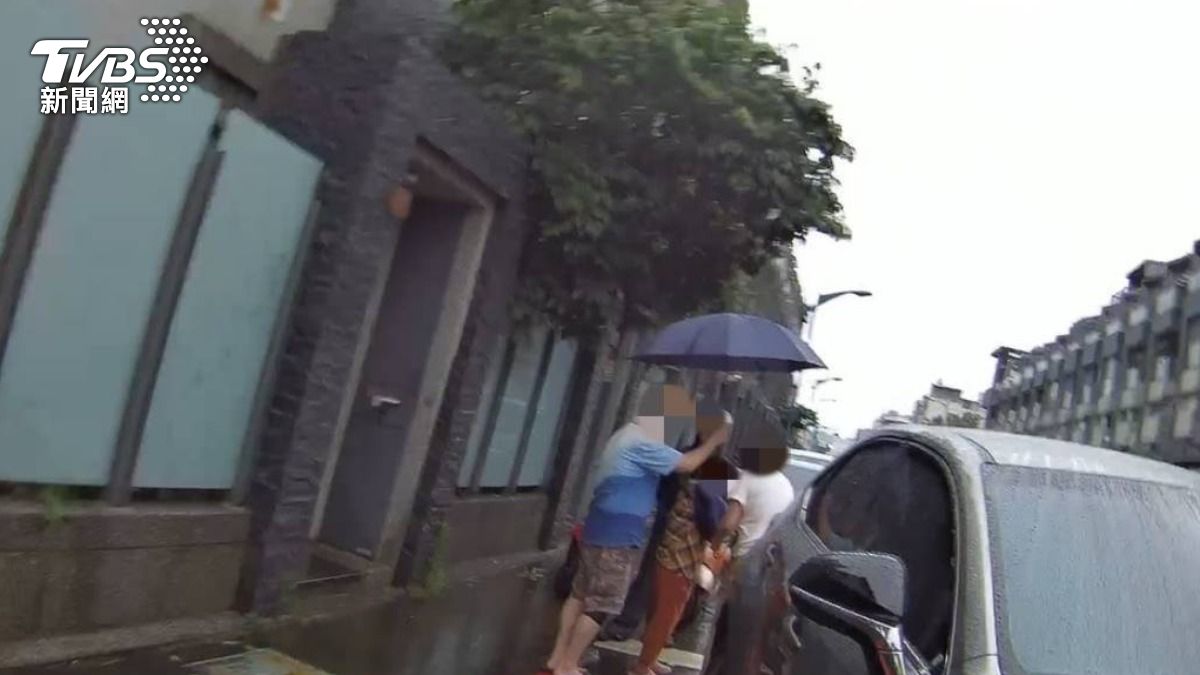 謝嬤右手打著石膏，淋雨徘徊在大同路上，一對熱心夫妻也立即上前關心撐傘。（圖／TVBS）