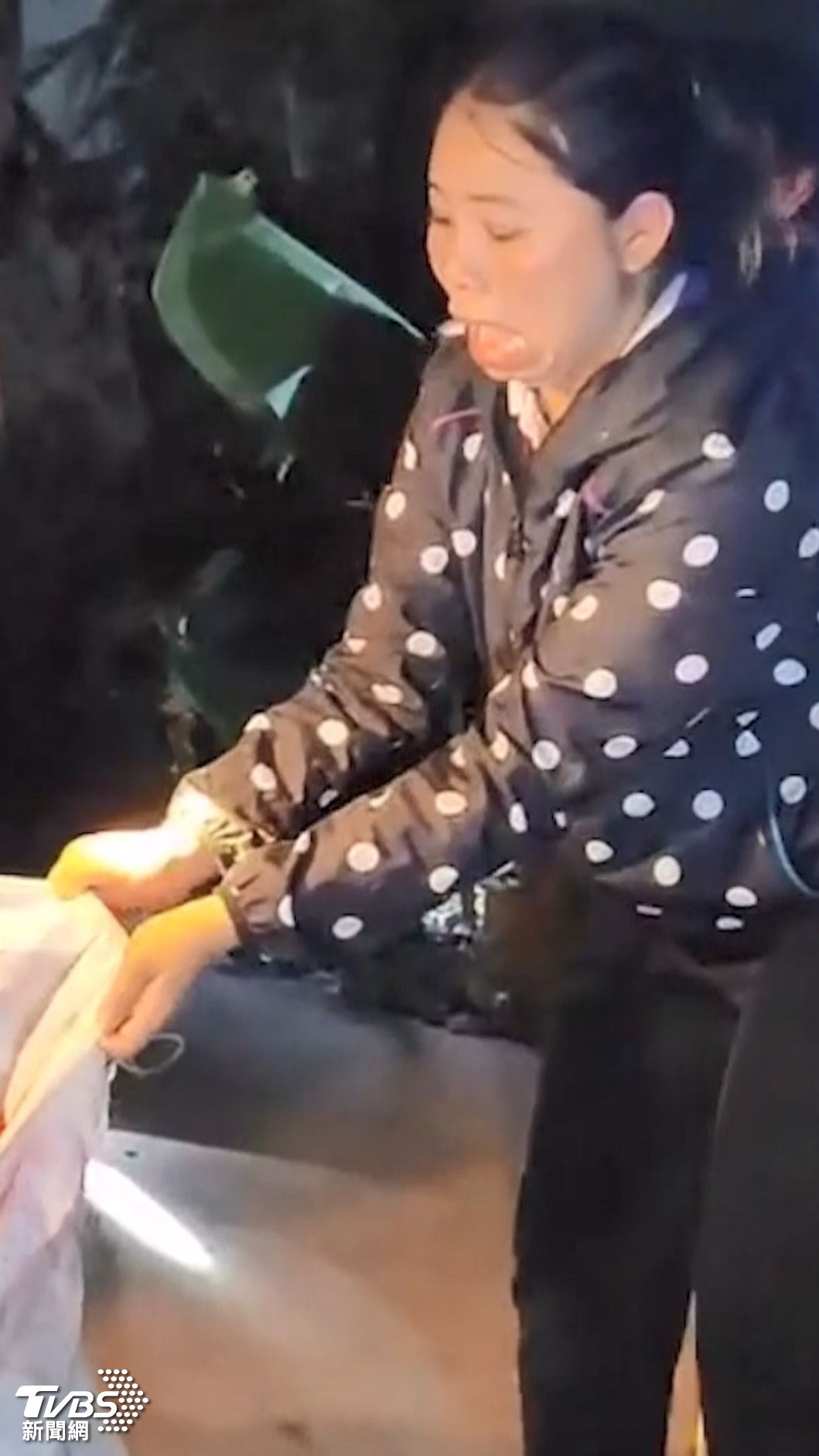 女志工驚恐地撐開麻袋,已無法表情管控。(圖/美聯社)