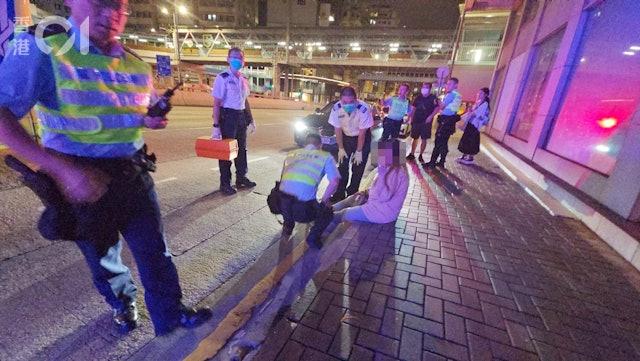 一名婦人危坐在漆咸道北馬路中間,警員將其帶到路邊,發現她情緒激動及受傷。(圖/香港01)