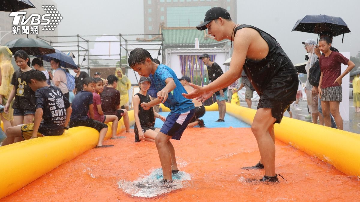 孩童在大雨中遊玩遊樂設施。（圖／華子琛攝）