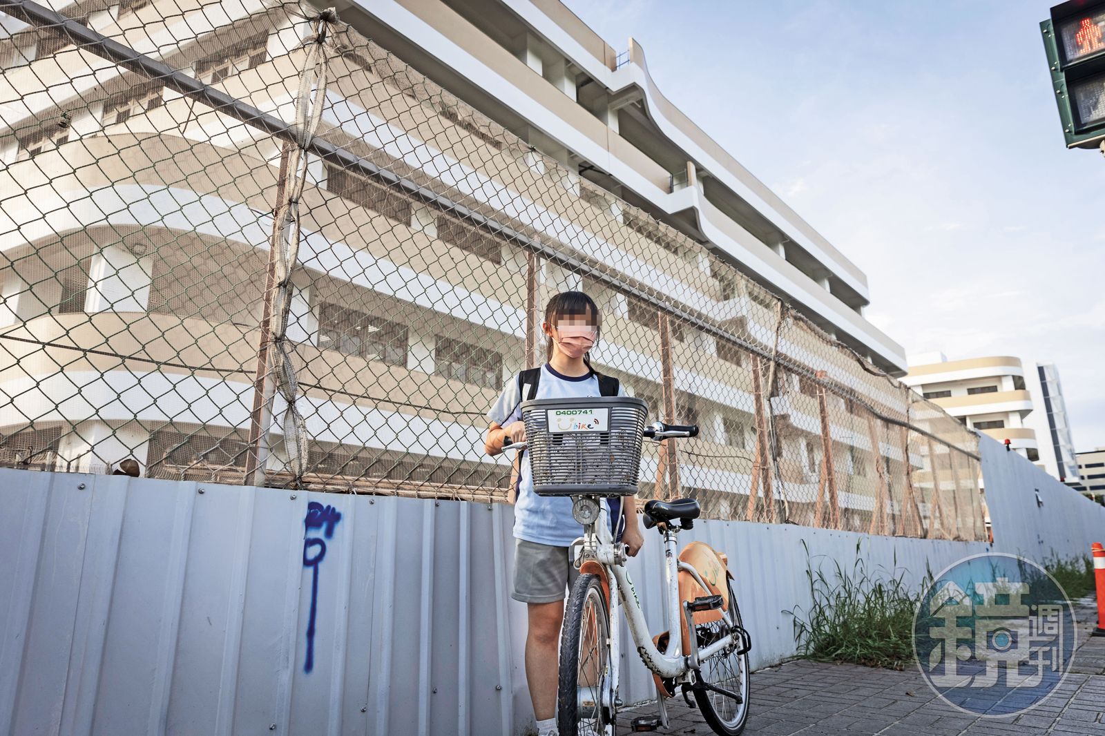竹科地區人口激增，學校建設速度跟不上入學需求，許多新校在未完工狀態下即招生。圖為一名國中生放學行經學校外圍的工地圍籬。（圖／鏡週刊）