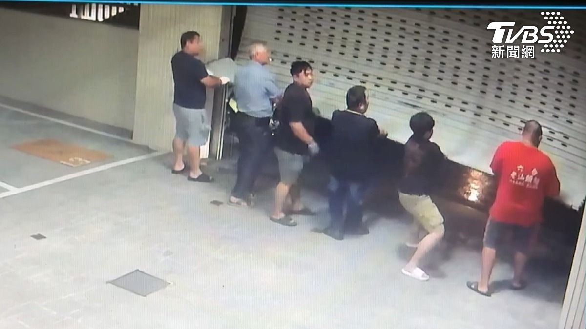 颱風丹娜絲6日晚間襲擊南台灣，在高雄大寮有鐵捲門被狂風吹掀，6名壯漢扶著鐵門，長達好幾分鐘。（圖／TVBS）