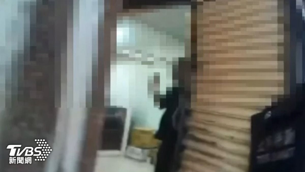 一名黑衣人見警方上門攻堅雙手舉高。(圖/TVBS)