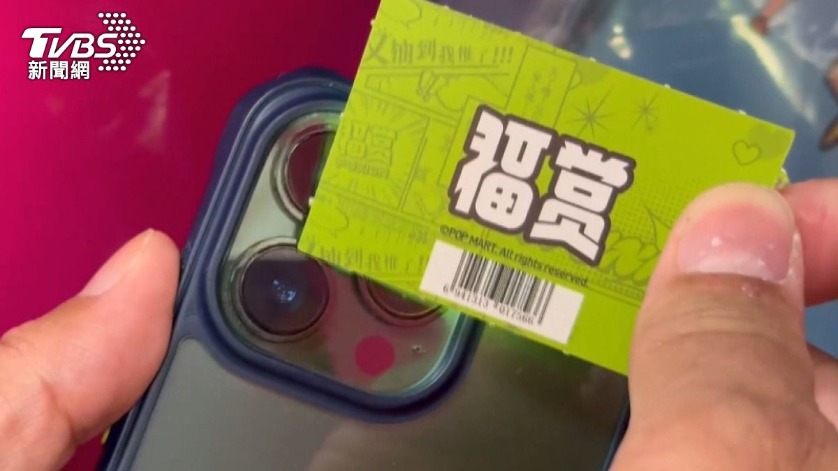 黑衣男拿手機「照透抽獎籤」。(圖/TVBS)