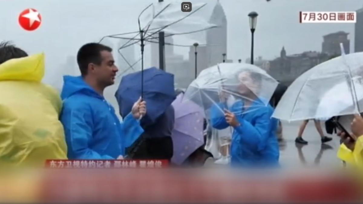 上海知名景點外灘，外國遊客的雨傘被強風吹到只剩傘架。（圖／上海東方衛視）