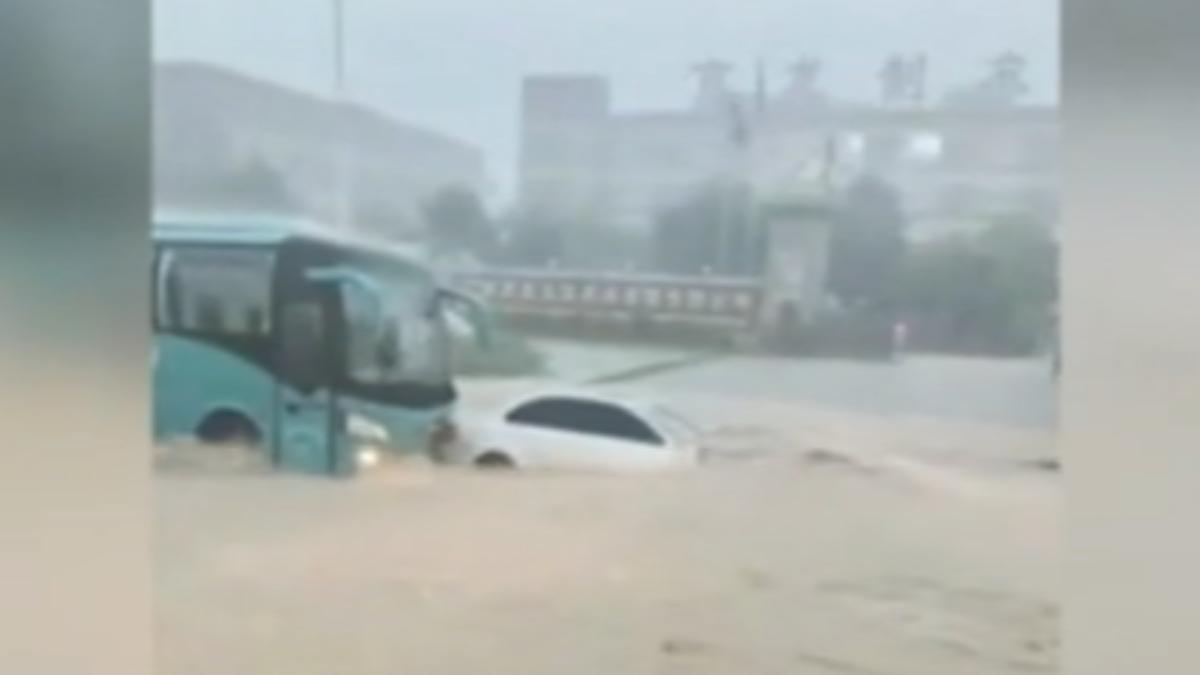 白色小客車淹水地段拋錨快被淹沒，大車用噸位擋住小車避免遭沖走。（圖／大陸央視）