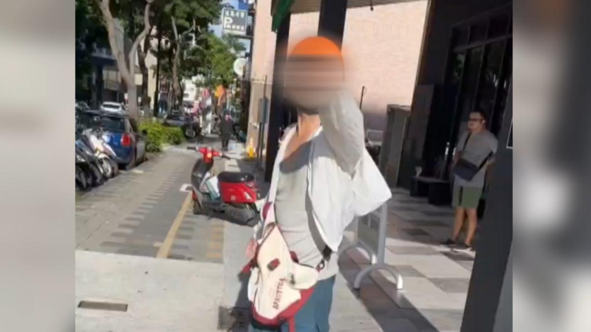騎樓圍了大批民眾,頭戴安全帽的男子和其他人發生激烈爭執,越講越氣,不只比中指甚至還出手推人(圖/翻攝社會事影音)