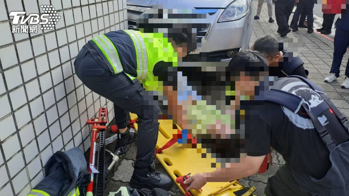 警消人員將受困車底的婦人救出送醫。(圖/TVBS)