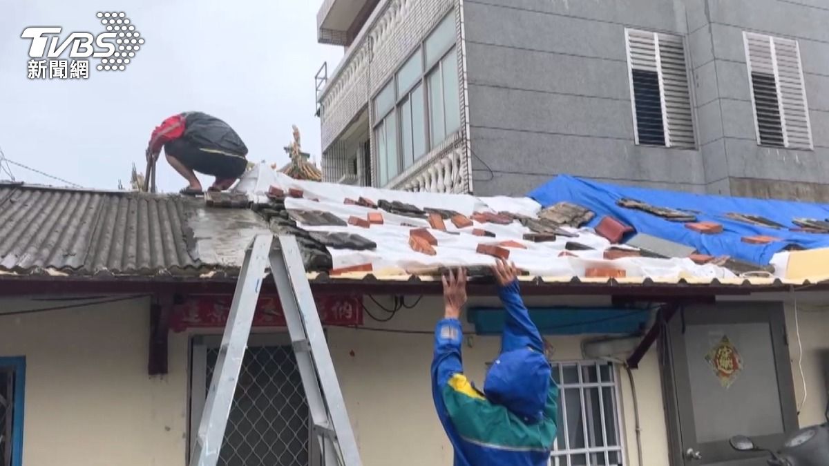 台南七股有居民冒險爬屋頂加固搶救家園。(圖/TVBS)