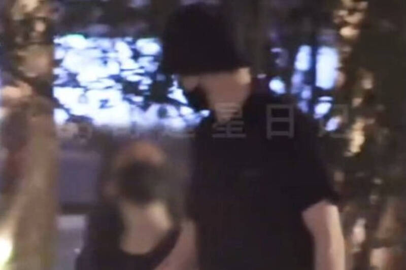 胡一天(右)被狗仔拍到與一名長髮正妹手牽著手散步。(圖/翻攝微博)