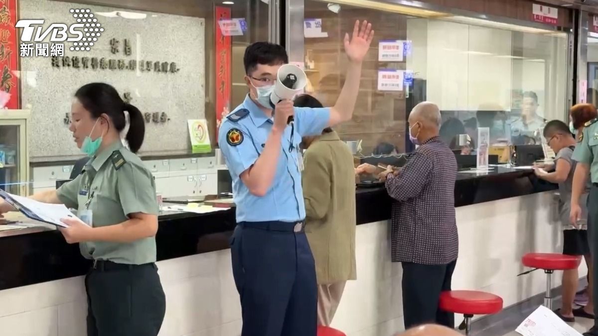 工作人員拿著大聲公，在掛號櫃台前 人工叫號。（圖／TVBS）