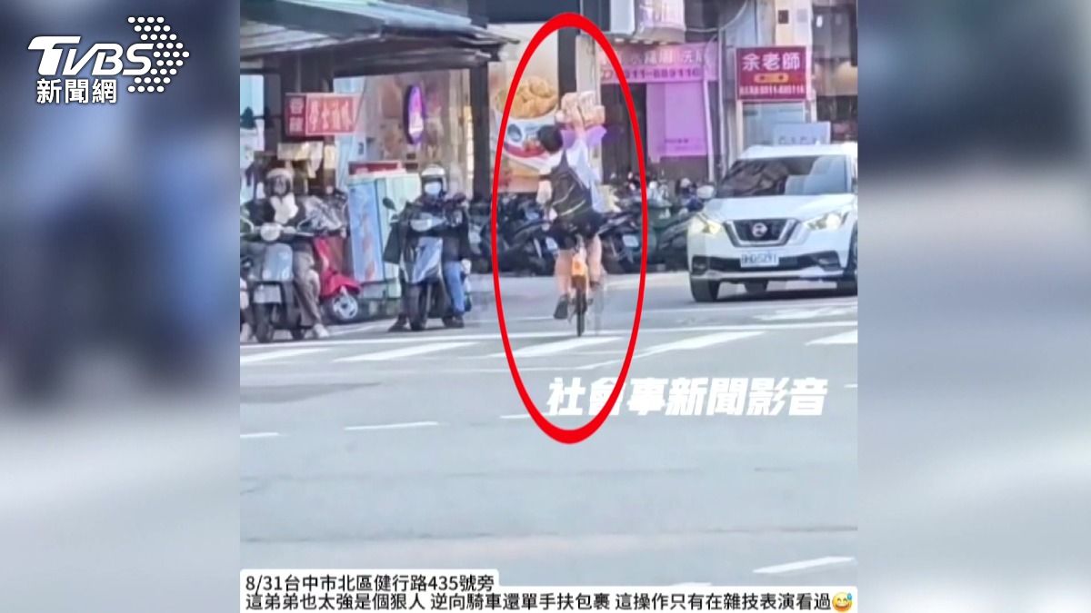 男大生Ubike載6包裹,單手騎車逆向闖紅燈!。(圖/翻攝社會事新聞影音)