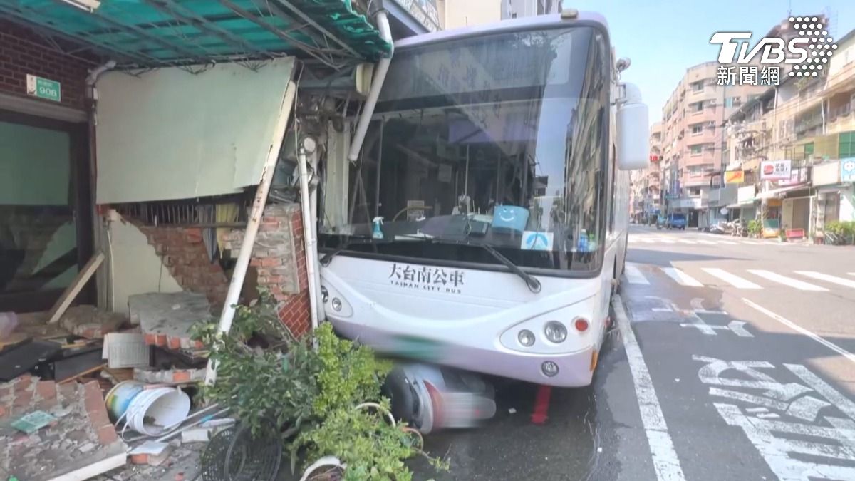 公車暴衝往民宅,撞斷消防栓,公車就卡在民宅前,門口的機車也被壓在公車底下(圖/TVBS)