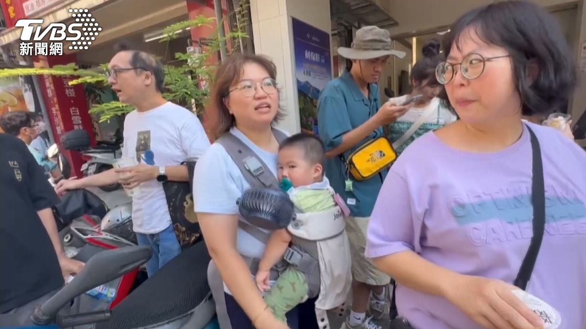 媽媽揹著幼童排隊,掛著小風扇幫孩子散熱。(圖/TVBS)