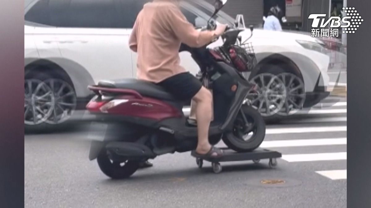 機車煞車疑似鎖死，前輪架在了有4顆小輪子的滑板上，婦人靠著自己的雙腳，以後輪驅動的方式來行駛（圖／翻攝Threads_liang.0209）