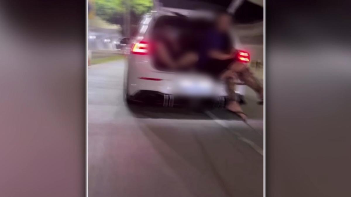 後車廂打開,兩名男子,一人負責控制拉繩,另一人則拿手機全程記錄這危險行為。(圖/TVBS)