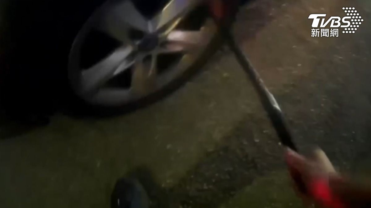 警掏出警棍插進輪胎鋼圈,想要男駕駛配合下車,還試圖安撫他的情緒(圖/TVBS)