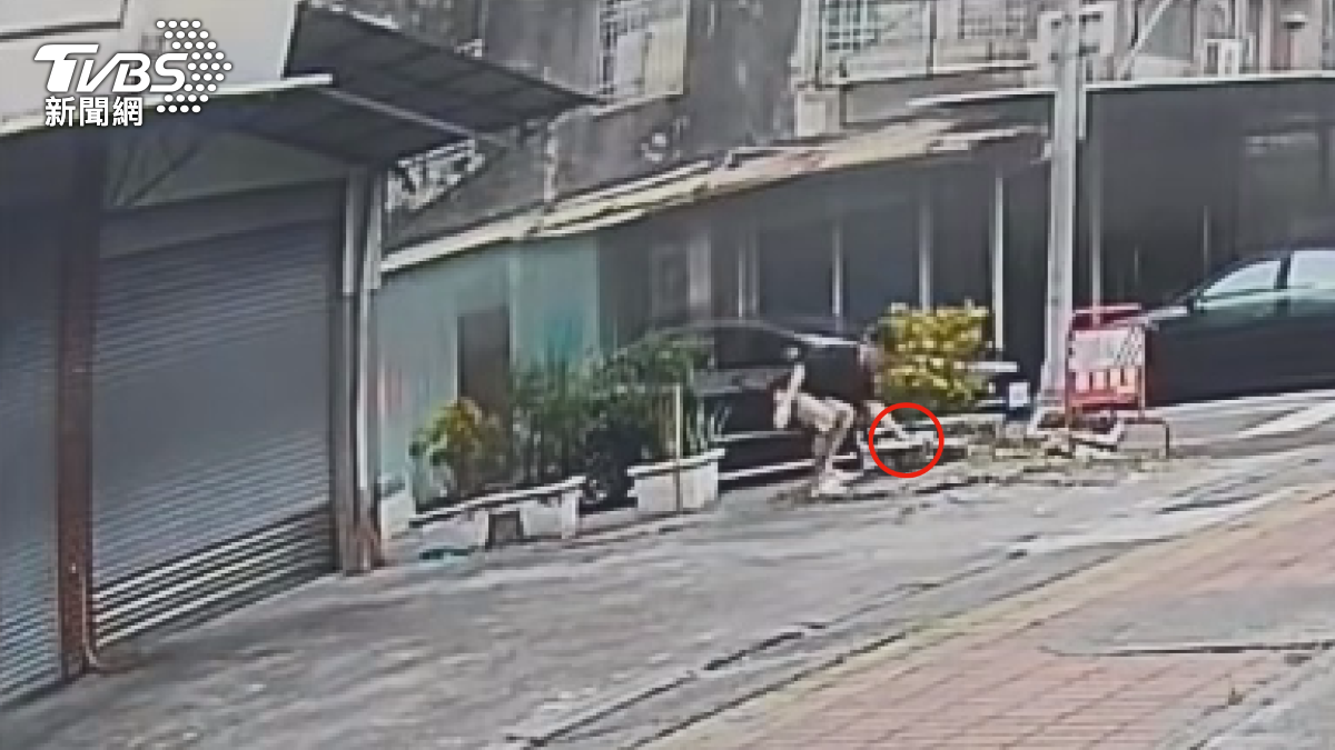 特斯拉副駕男子在路邊撿起石頭,上前對趙姓男子嗆聲。(圖/TVBS)