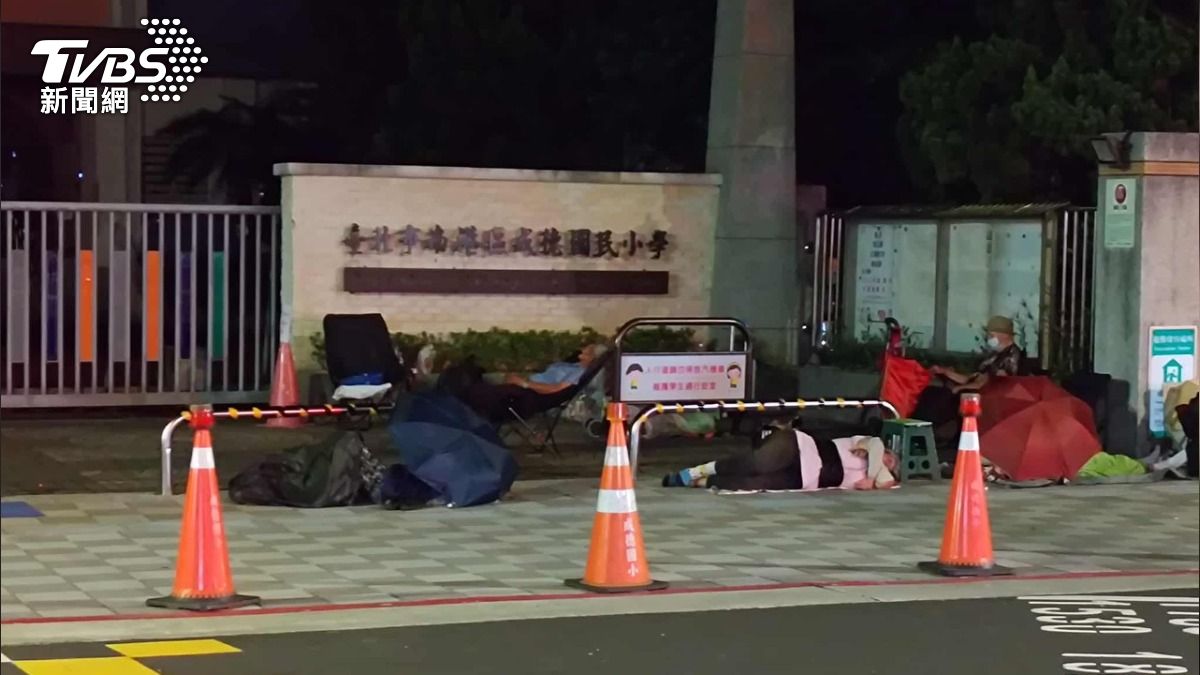 18日凌晨兩點,民眾目擊北市國小外有民眾夜排,不只都是長輩,還直接睡在路邊。(圖/我是南港人提供)