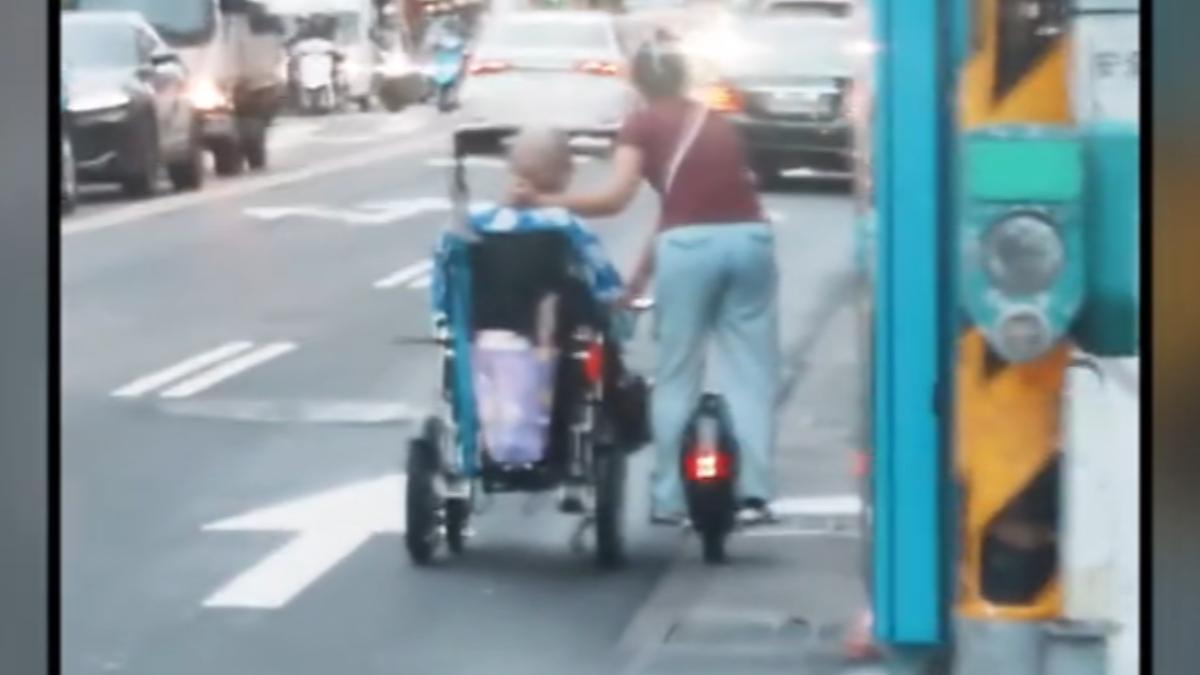 女在馬路上一邊騎平衡車一邊推輪椅,目擊者憂長輩危險。(圖/民眾提供)