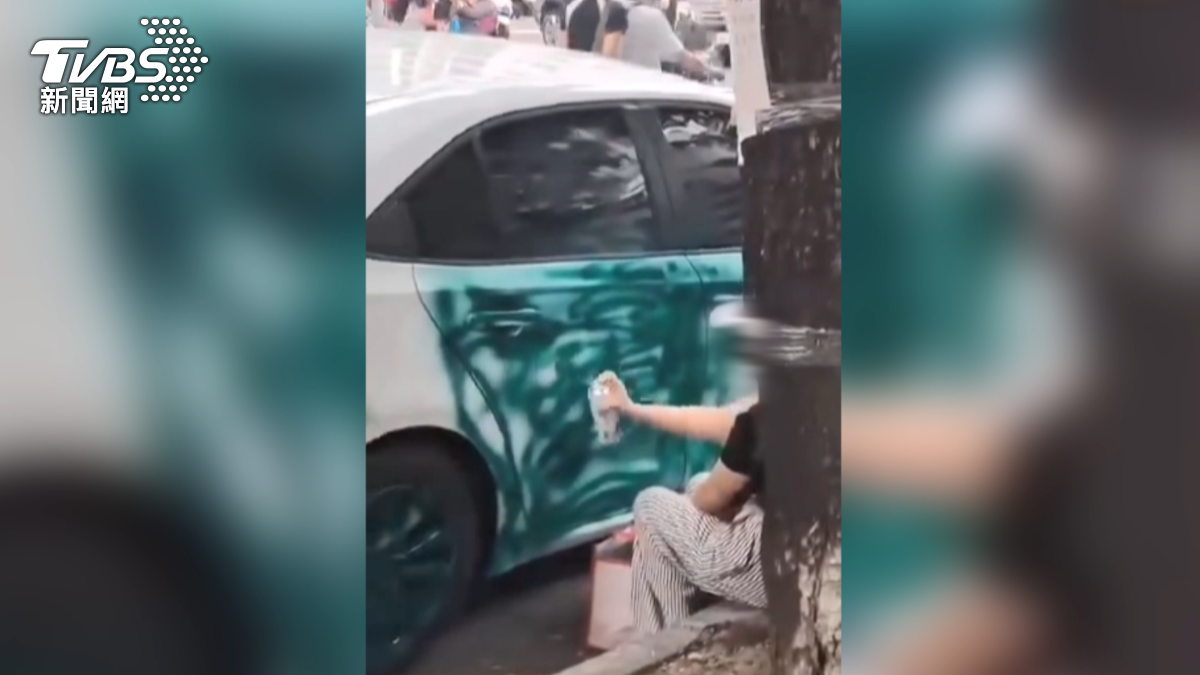 一名戴著帽子和口罩的女子拿著噴漆對一輛白色小客車右側車門噴灑綠色油漆，此舉引起許多學生和路人的圍觀。（圖／翻攝Threads_felix_k203）