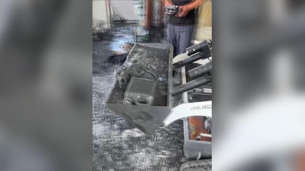 工作人員操控的不是玩具車,而是能鏟起淤泥並移至屋外的小型遙控山貓鏟土機。(圖/民眾提供)