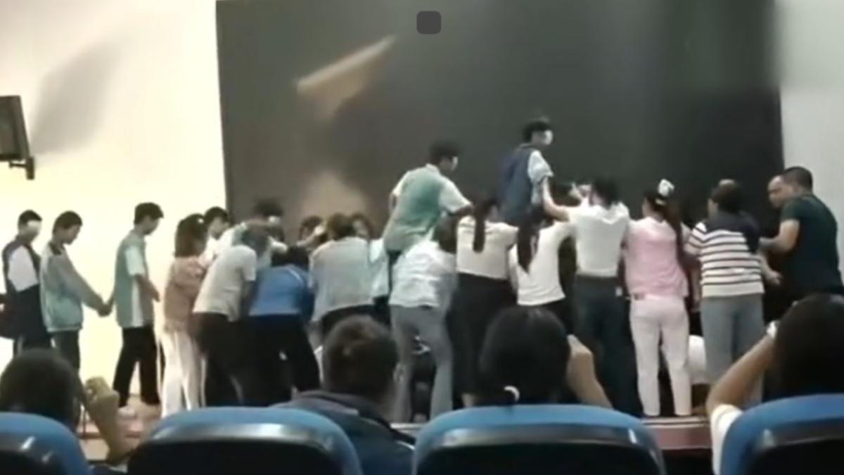 在老師催促下,學生不得不從跪在地上的「人橋」背上踩過。(圖/網上流傳影片)