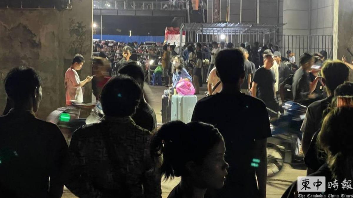 大批男女站在西港中國城園區外，許多人帶著大包小包的行李。（圖／柬中時報）