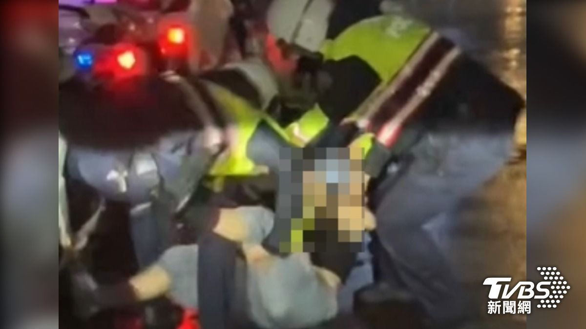 雨中擋車跳舞,女遭3警扛出車道。(圖/TVBS)