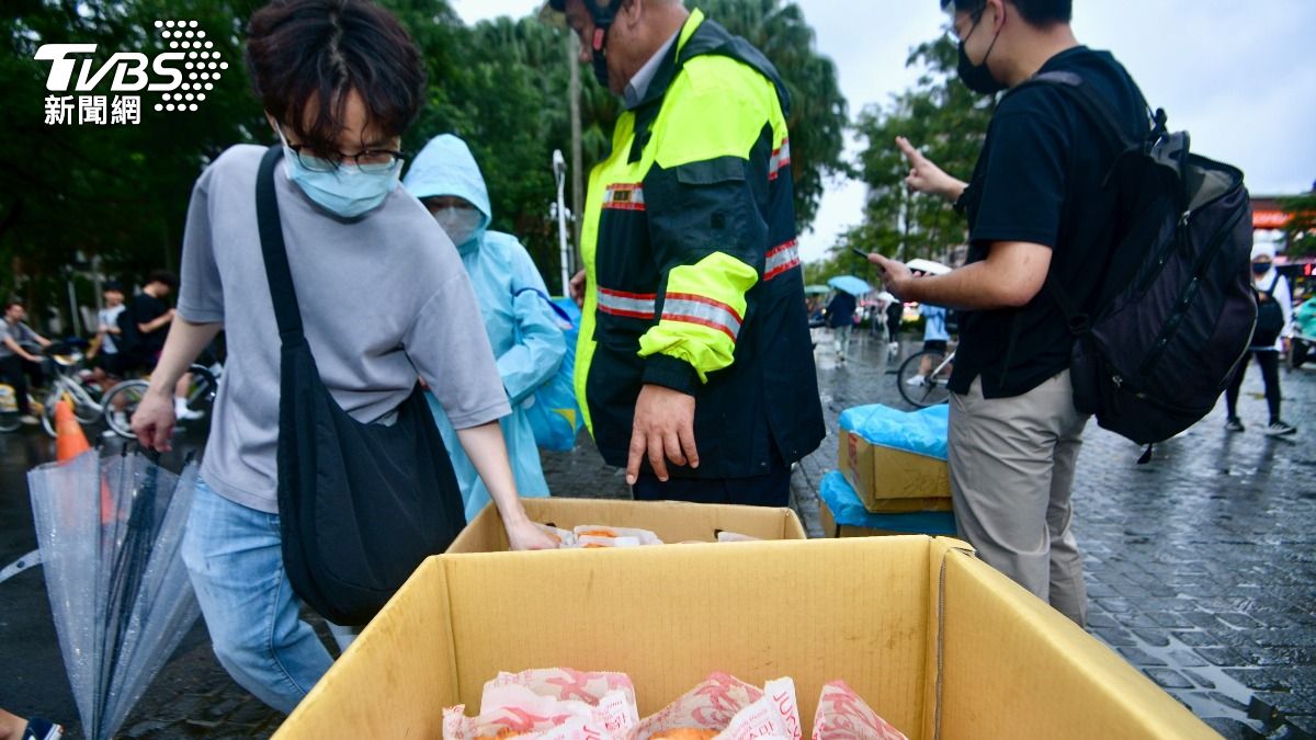 學生和民眾排隊在台大校門口廣場領免費雞排,校警在一旁協助。(圖/胡瑞麒攝)