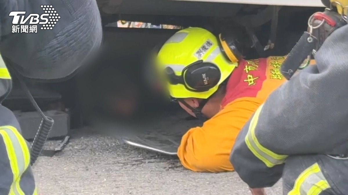 救援人員趴在車底下救人,發現物流車車頭底下的女乘客雖然被底盤夾住。(圖/TVBS)