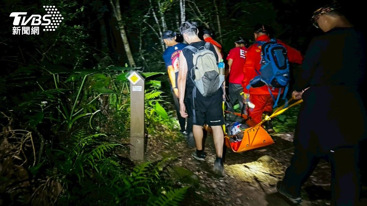 李姓女山友因頭部撕裂傷且出現嘔吐不停的情況,消防員以徒手搬運方式接駁傷者下山。(圖/TVBS)