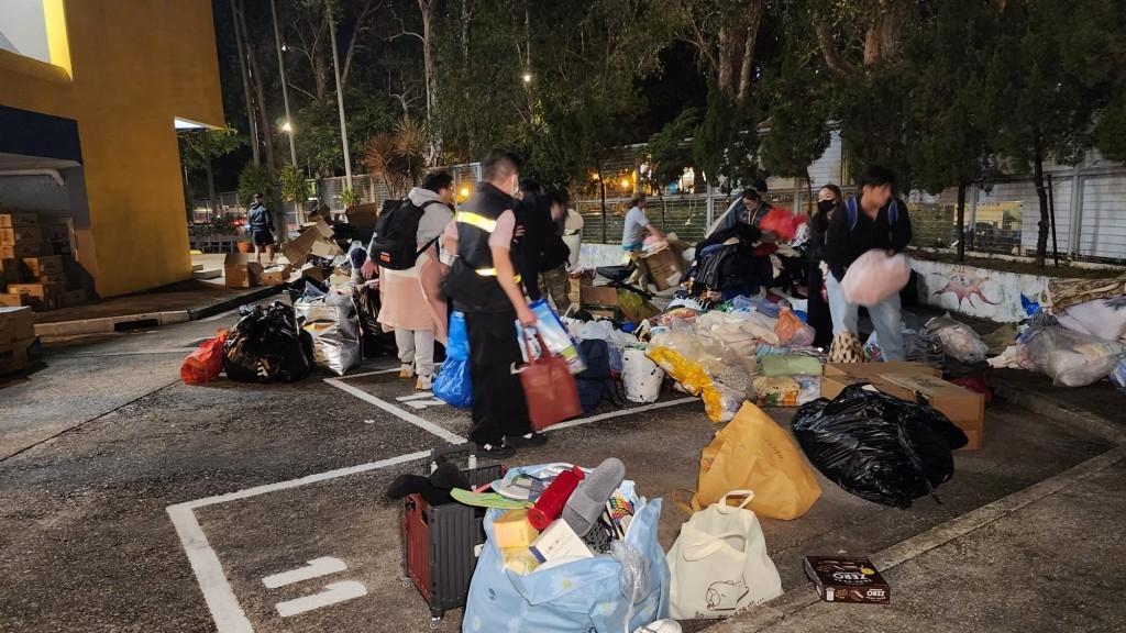 大批街坊協助搬運箱裝礦泉水等生活必需品。(圖/星島日報)