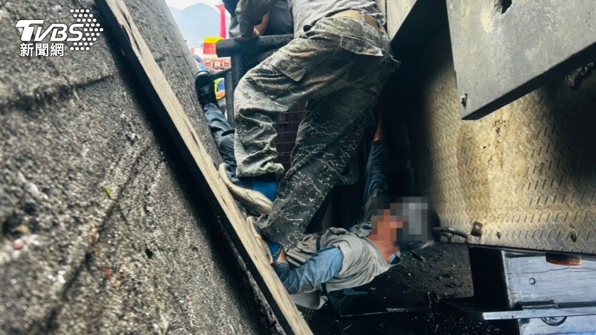 現場指揮吊車作業的胡姓男子被夾困在吊車與堤防中,動彈不得。(圖/TVBS)