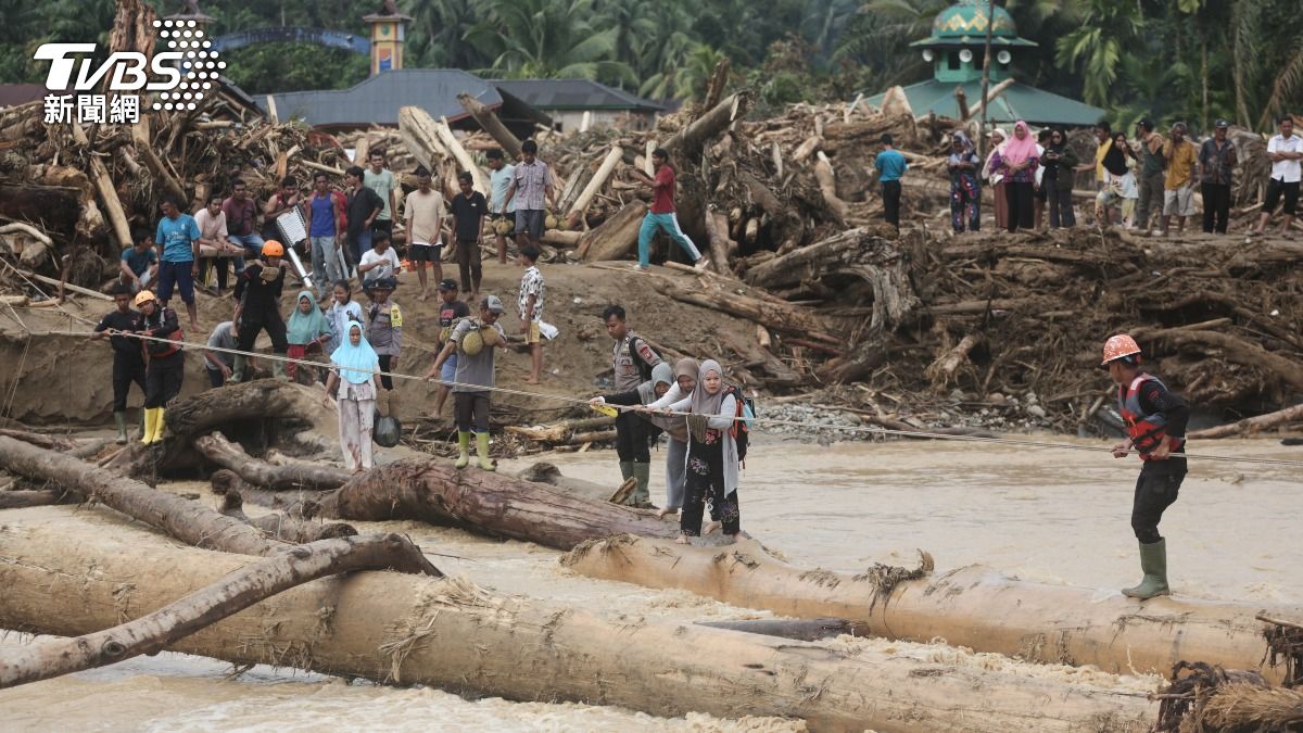 東南亞多國近日遭遇罕見豪雨襲擊，洪水與土石流淹沒城鎮。圖為印尼蘇門答臘，洪水倖存者使用原木渡河。（圖／達志影像美聯社）